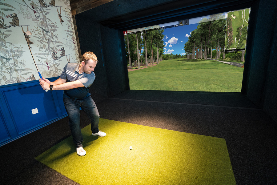 A man practicing his swing with a golf simulation system.