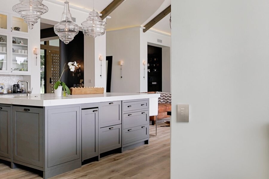 A kitchen space featuring Lutron lighting fixtures with a Lutron wall panel on a wall in the foreground.
