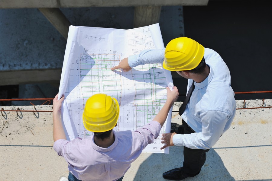 Two engineers check on the blueprint design of a new build.