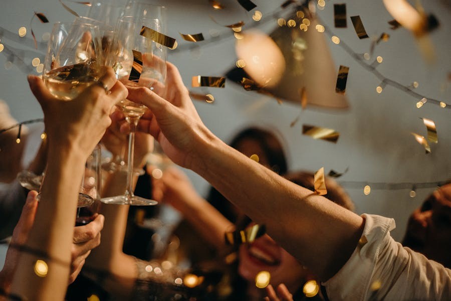 A group of people toasting on New Year’s Eve while golden confetti falls over them.