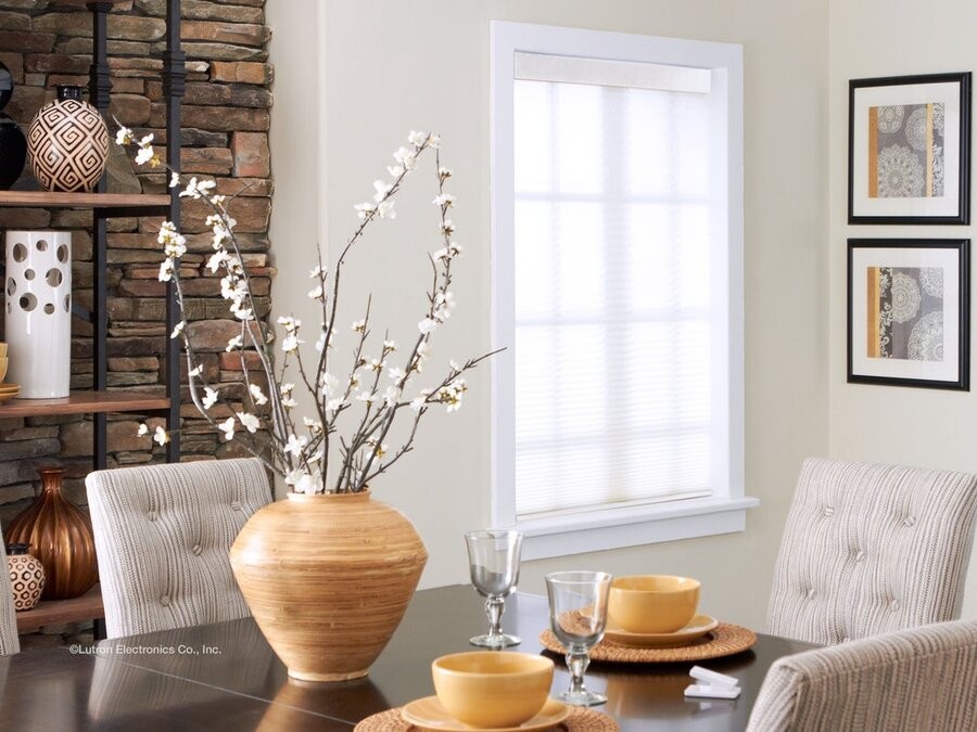 A dining room with a window in the back featuring Lutron automated window treatments.