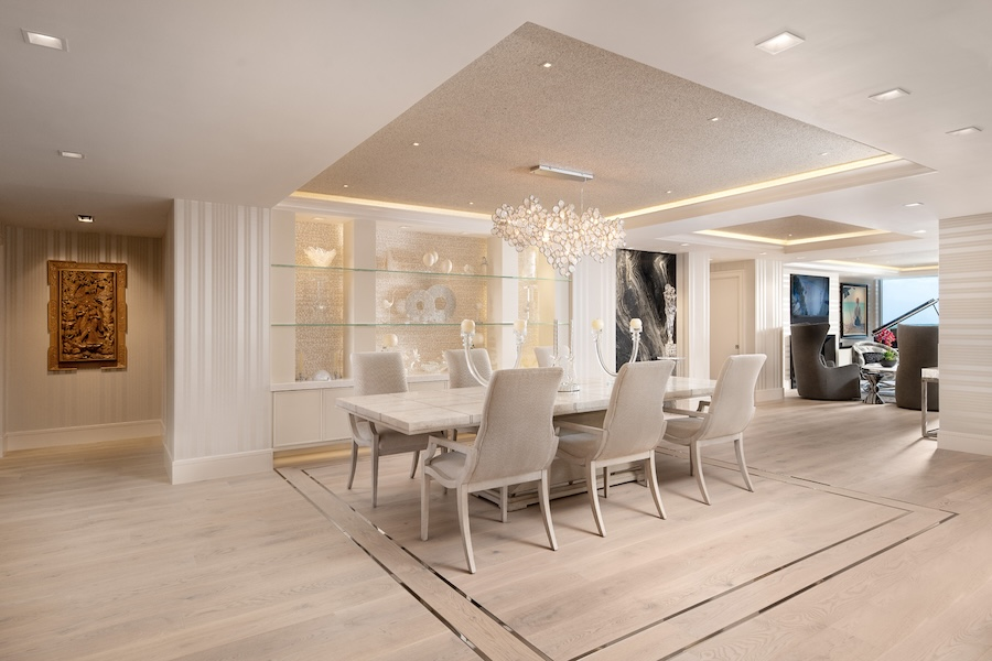 open dining and living space with square trim lighting details in the ceiling and under-shelf illumination highlighting decor